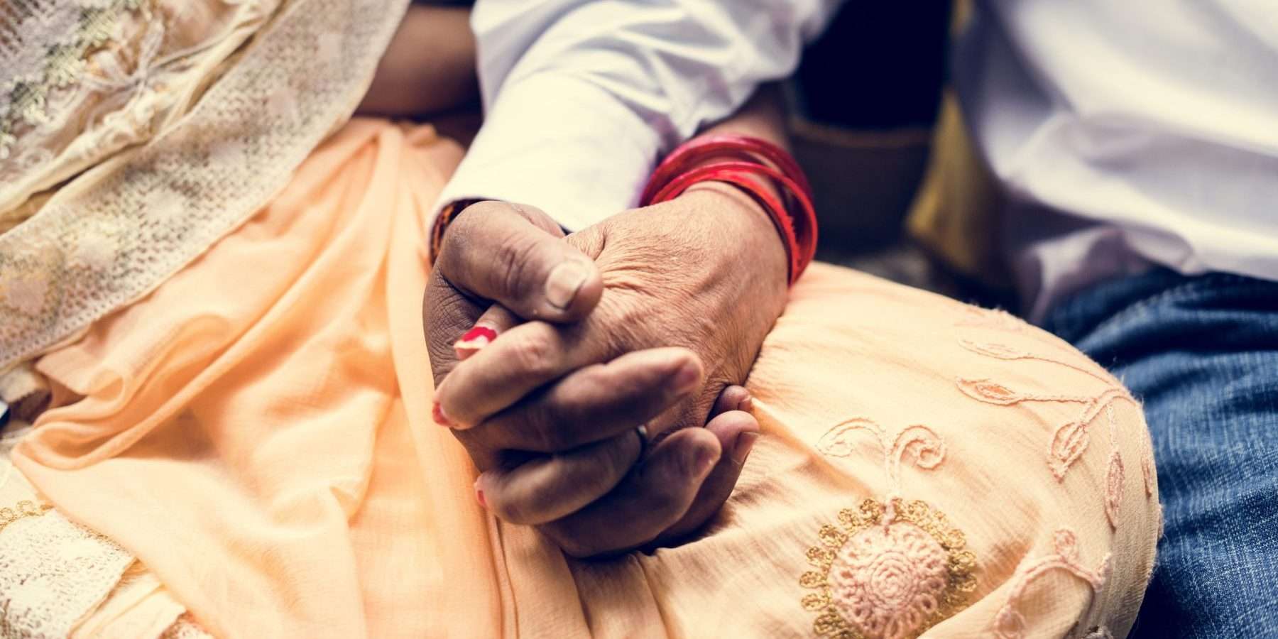 Manos entrelazadas de una pareja india sentada, símbolo del Nakshatra Uttara Phalgunī en la astrología védica